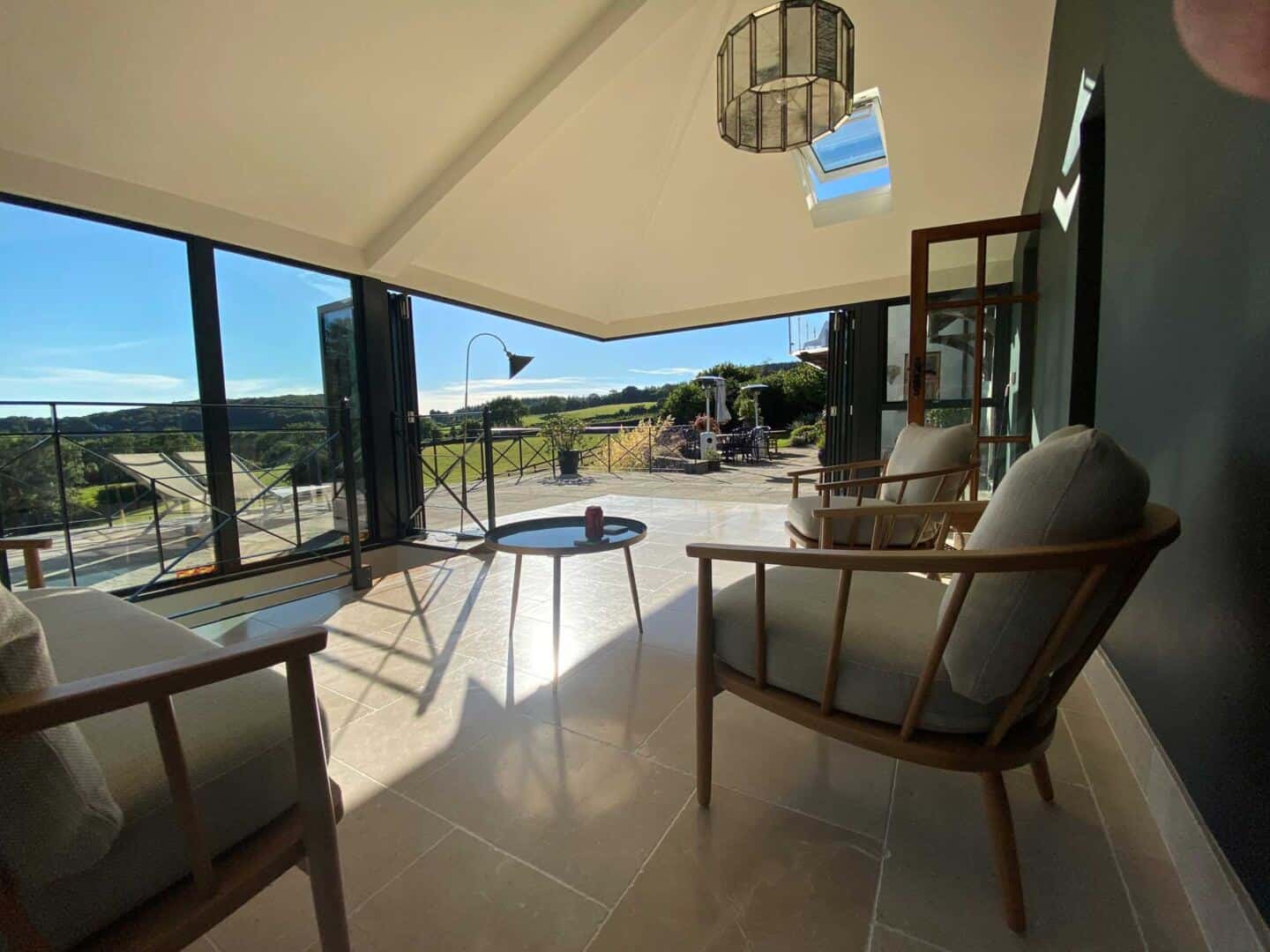 These cornerless aluminium bi-fold doors allow the natural light to flood in whilst connecting this sitting room to the garden.