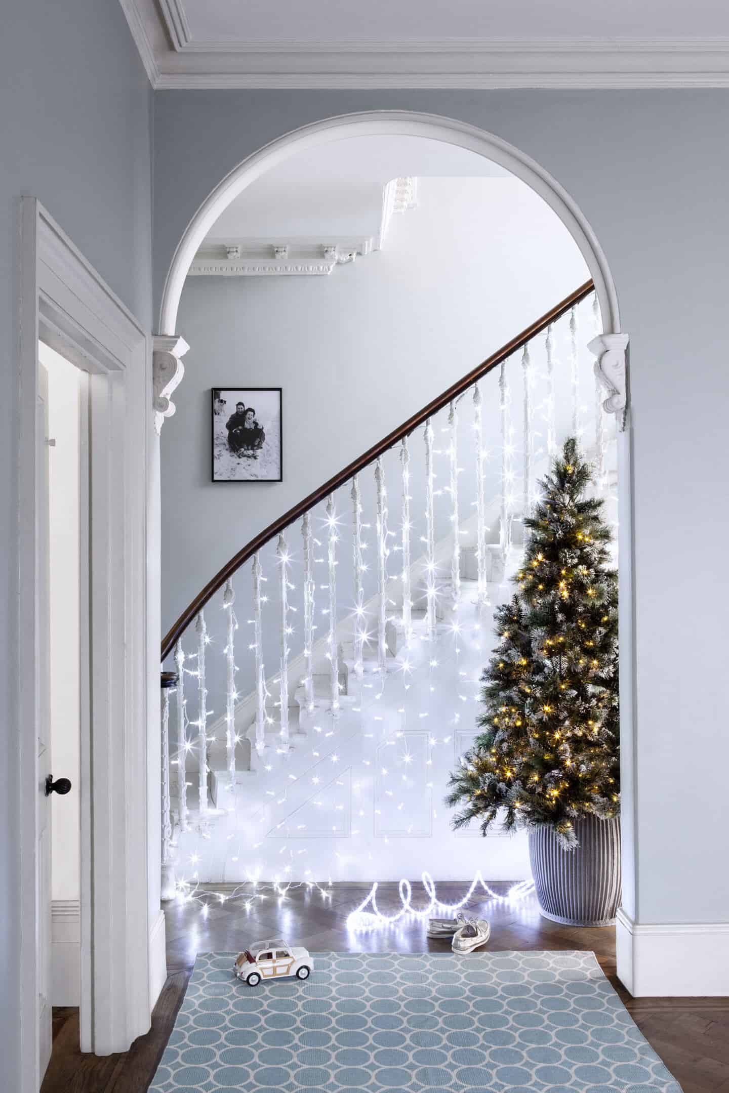 A staircase decorated for Christmas with a curtain of sparkly fairy lights