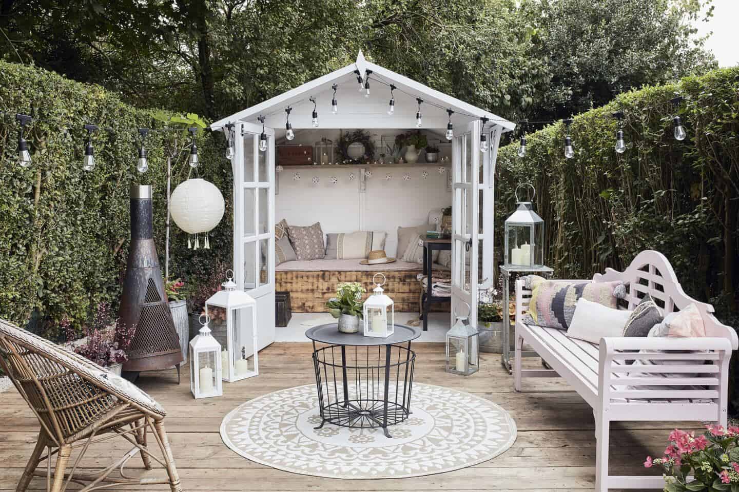 A garden shed used as a summer house on a deck with hanging festoon lights