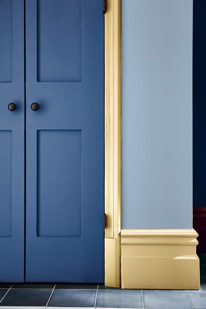 A blue door with yellow surround and yellow skirting board. Image c/o Little Greene 