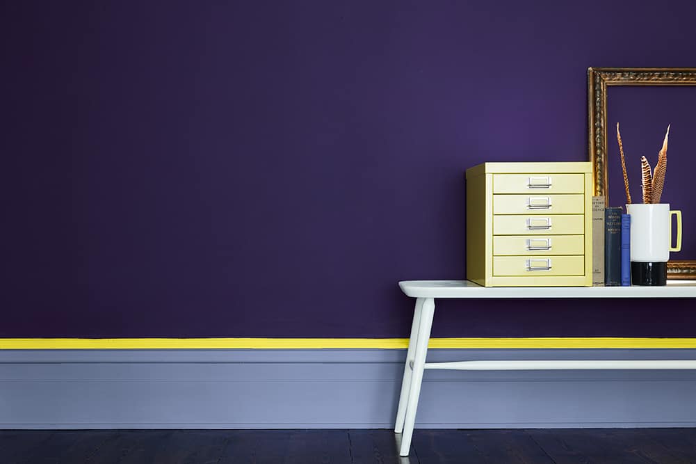 A high painted skirted board with a bench in front of a purple wall