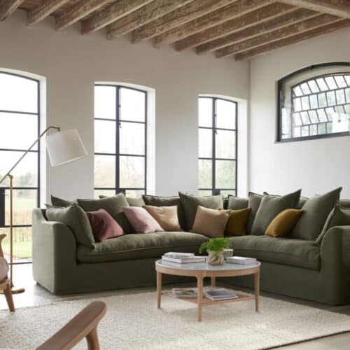 A living room with large windows, a corner sofa and a boucle rug