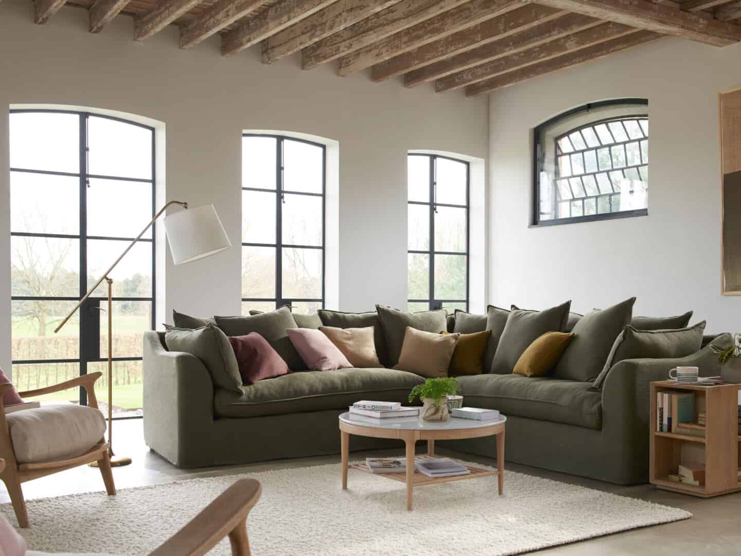 A living room with large windows, a corner sofa and a boucle rug