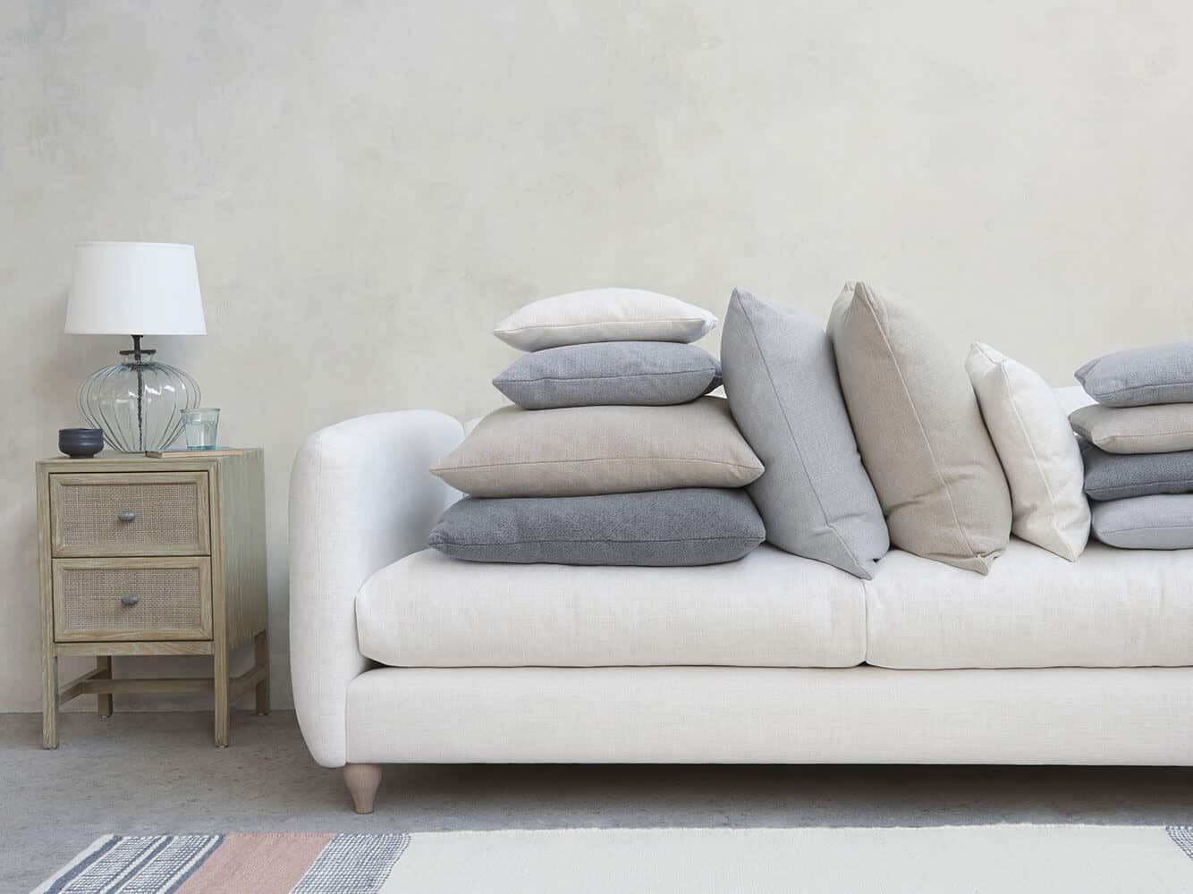 A squishy white sofa in bamboo fabric is covered in cushions. Bamboo is a great material for sustainable interior design