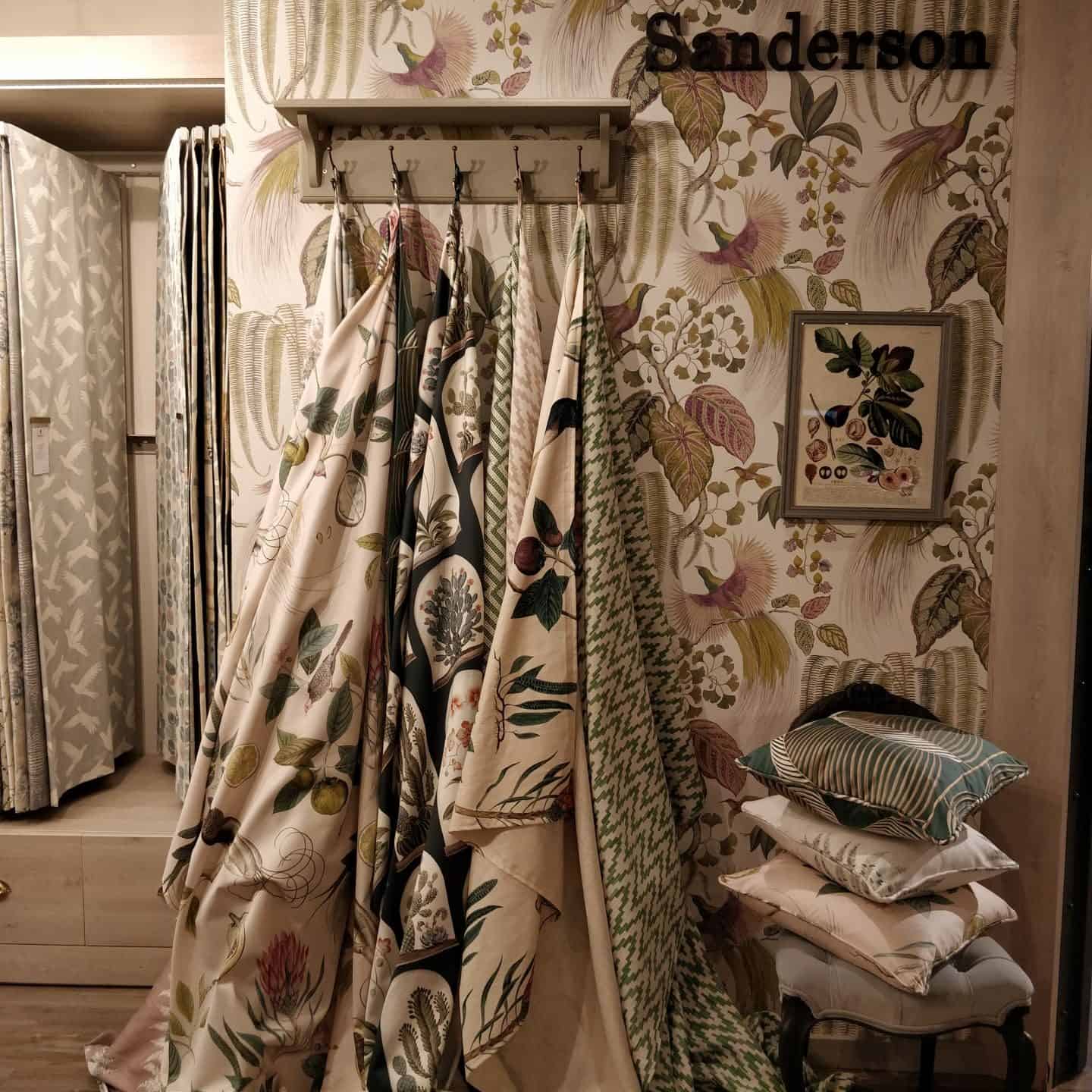 A display of fabrics and cushions and wallpaper by Sanderson