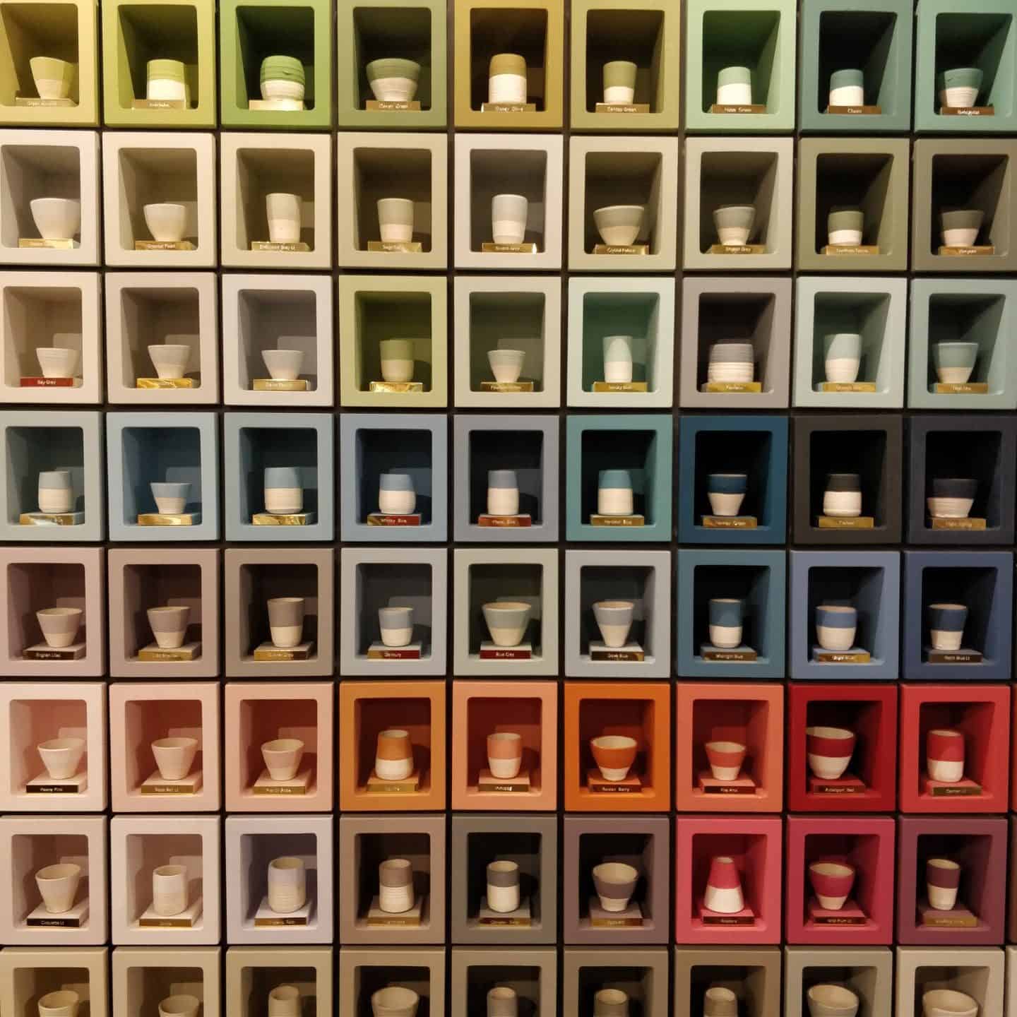 A selection of paint colours displayed in small cubes containing painted pots.