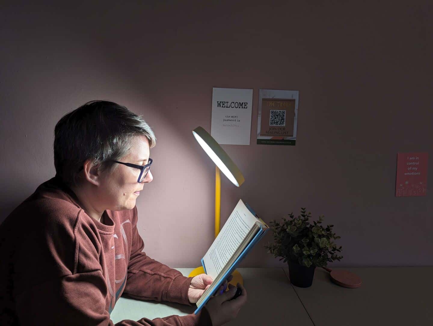 A woman in her forties sat reading a book about 20-cms from the Lumie Task lamp