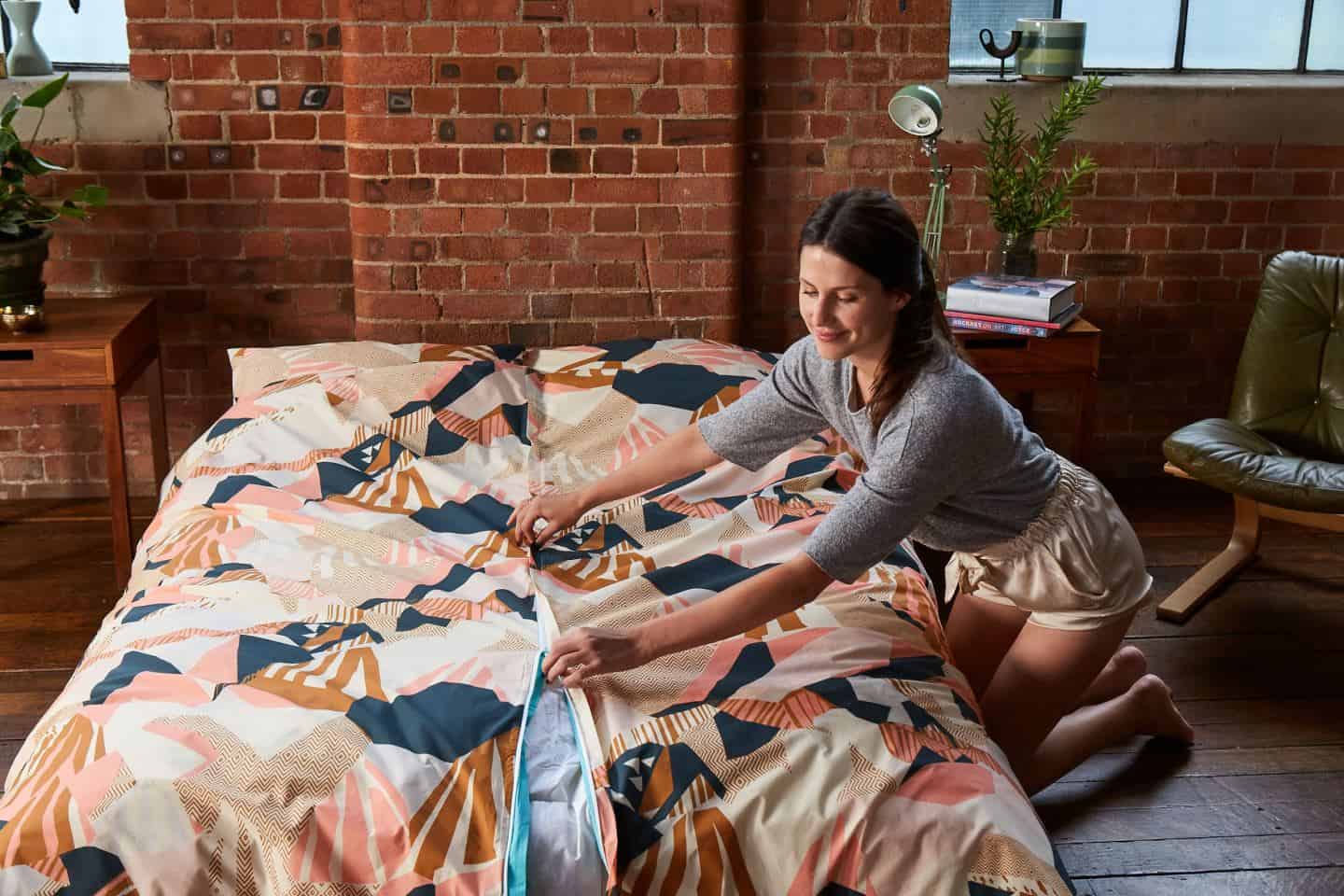 Koa revolutionary duvet cover. A woman closes the central zip once the duvet has been positioned inside. The easy way to change a duvet cover