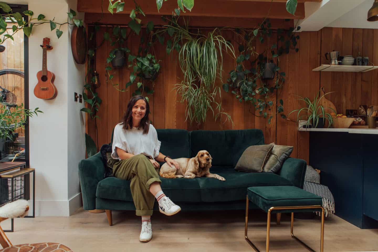 Author and biophilic design expert Marianna Popejoy sat on a green velvet sofa with her dog