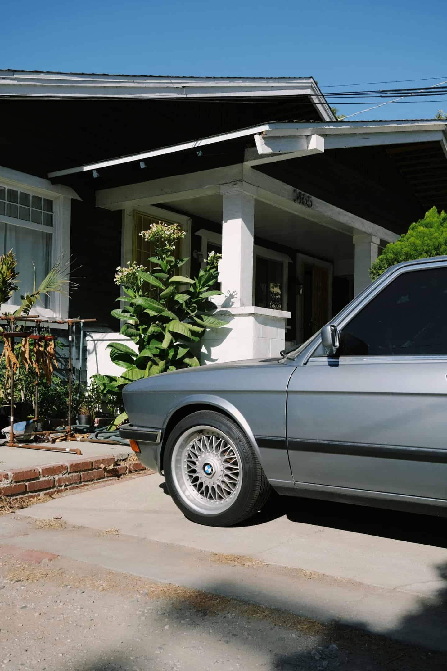 A silver BMW car parked outside a house on a concrete driveway