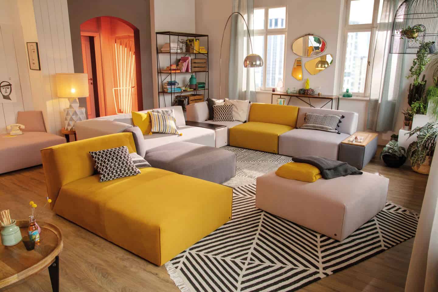 Pantone Colour of the Year 2021 - Illuminating. The colour psychology behind using yellow in interiors. A modular sofa from Tom Tailor Home with sections in yellow and grey in a living room