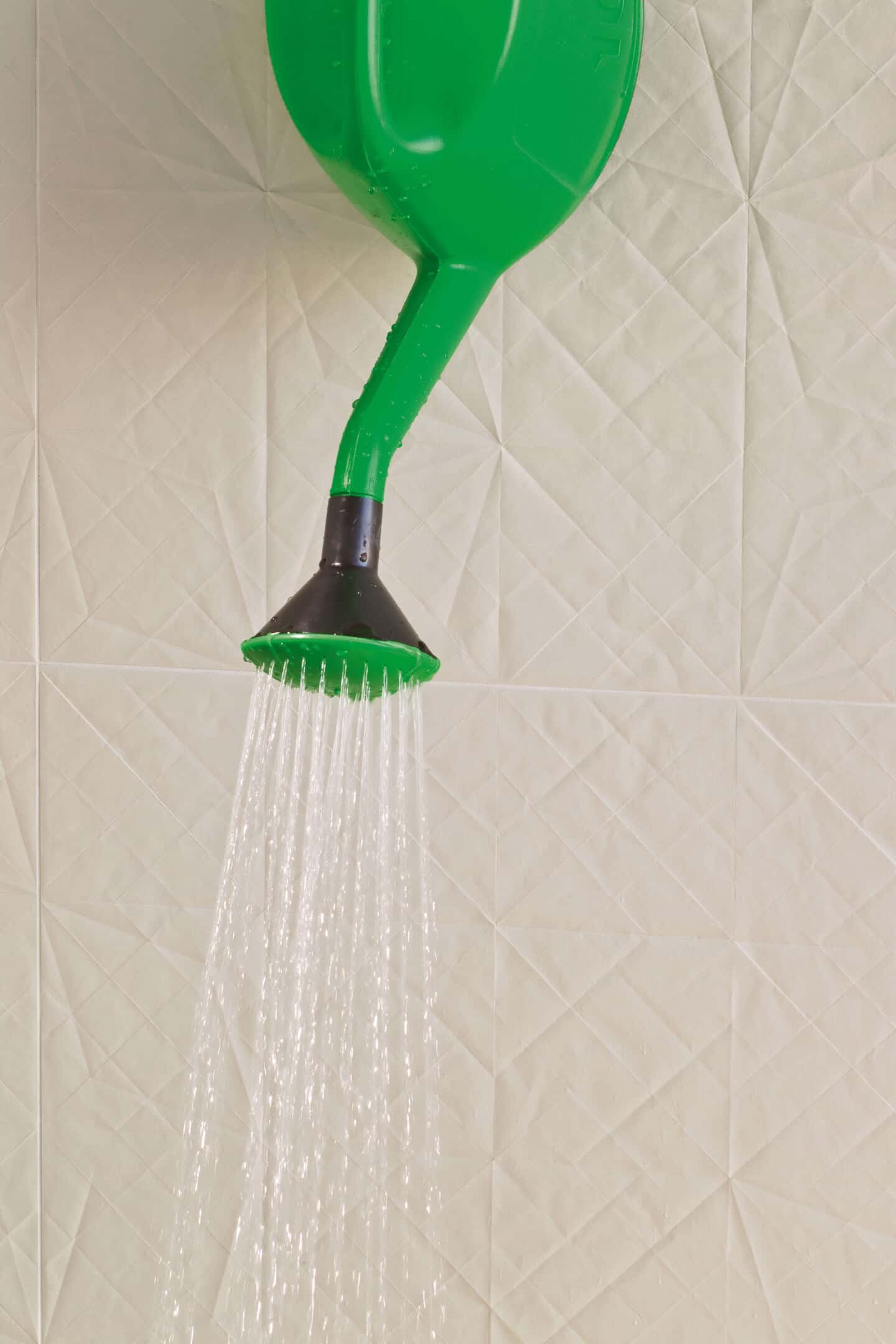 White textured wall tiles. A watering can is being poured out in the foreground.