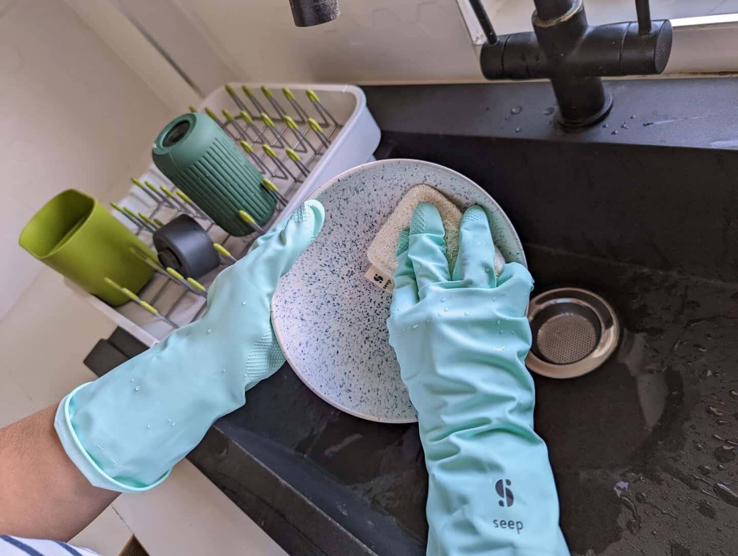 Plastic-free cleaning products from Seep used to wash a blue Denby plate over a black granite sink