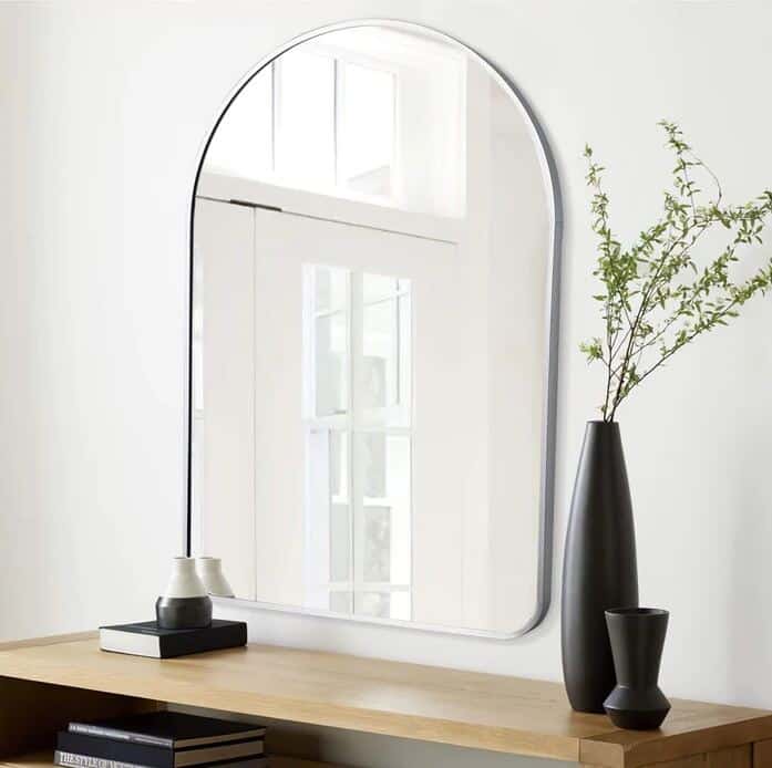 A small arched mirror from neutypechic wall-mounted above a sideboard 