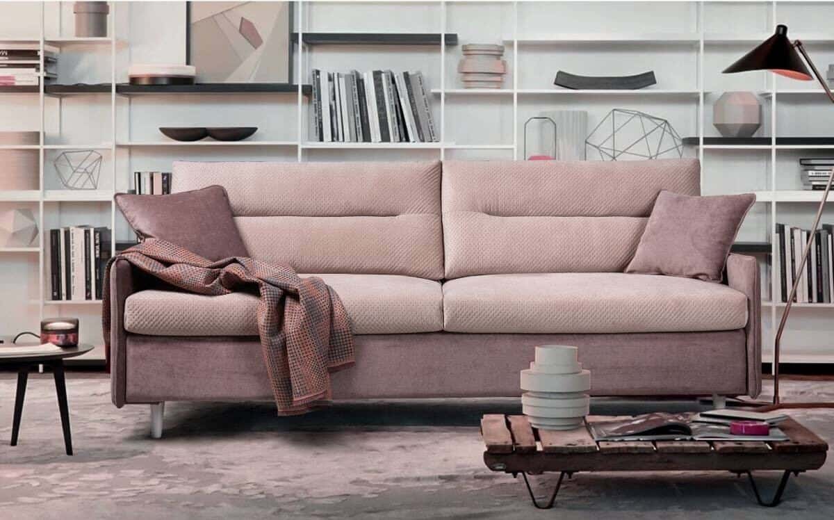 How to choose the perfect sofa for your lifestyle. Pink sofa bed in front of floor to ceiling shelving