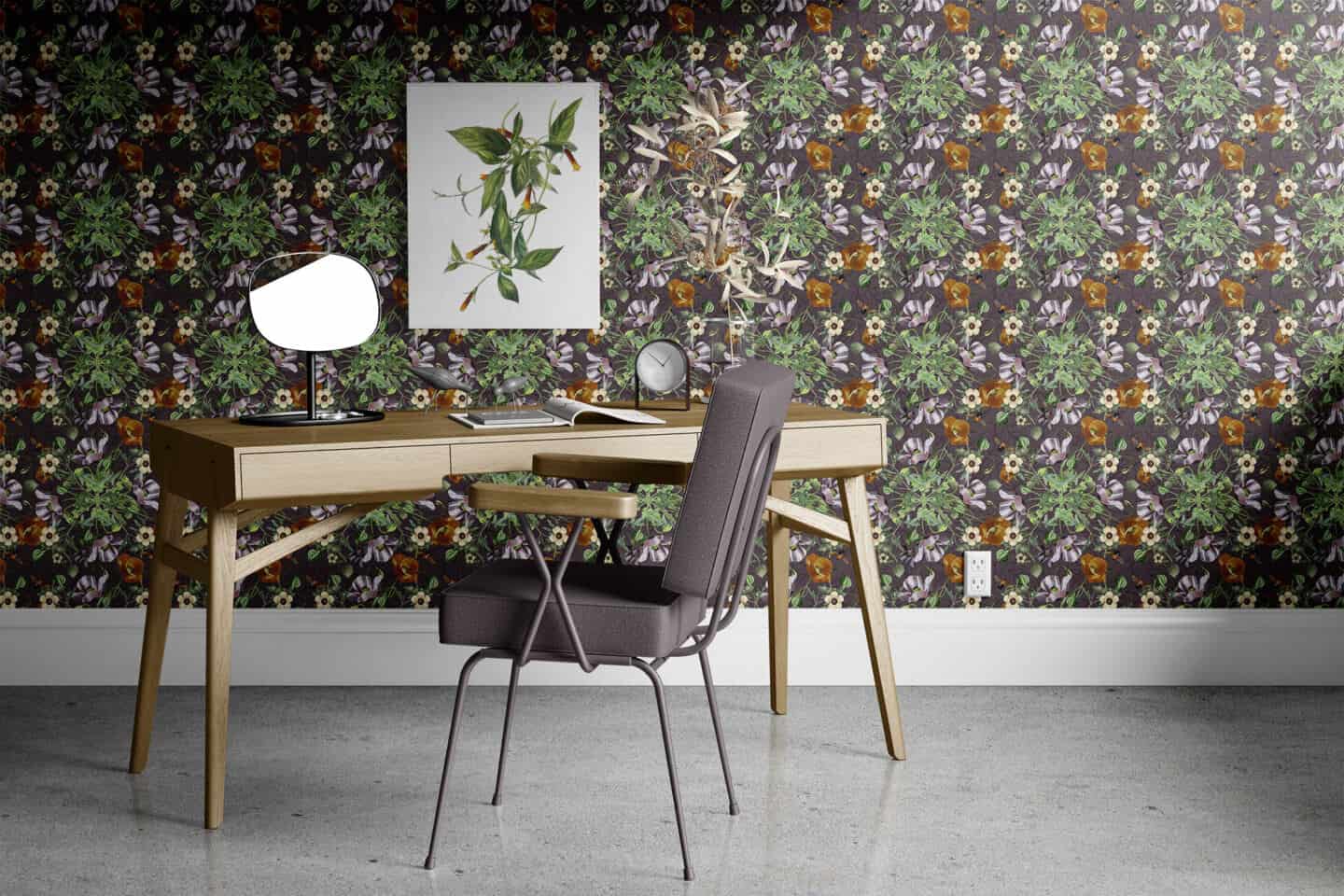 A home office featuring aScandi-style oak desk and grey padded chair. Black botanical wallpaper on the wall featuring red and pink flowers and green leaves.