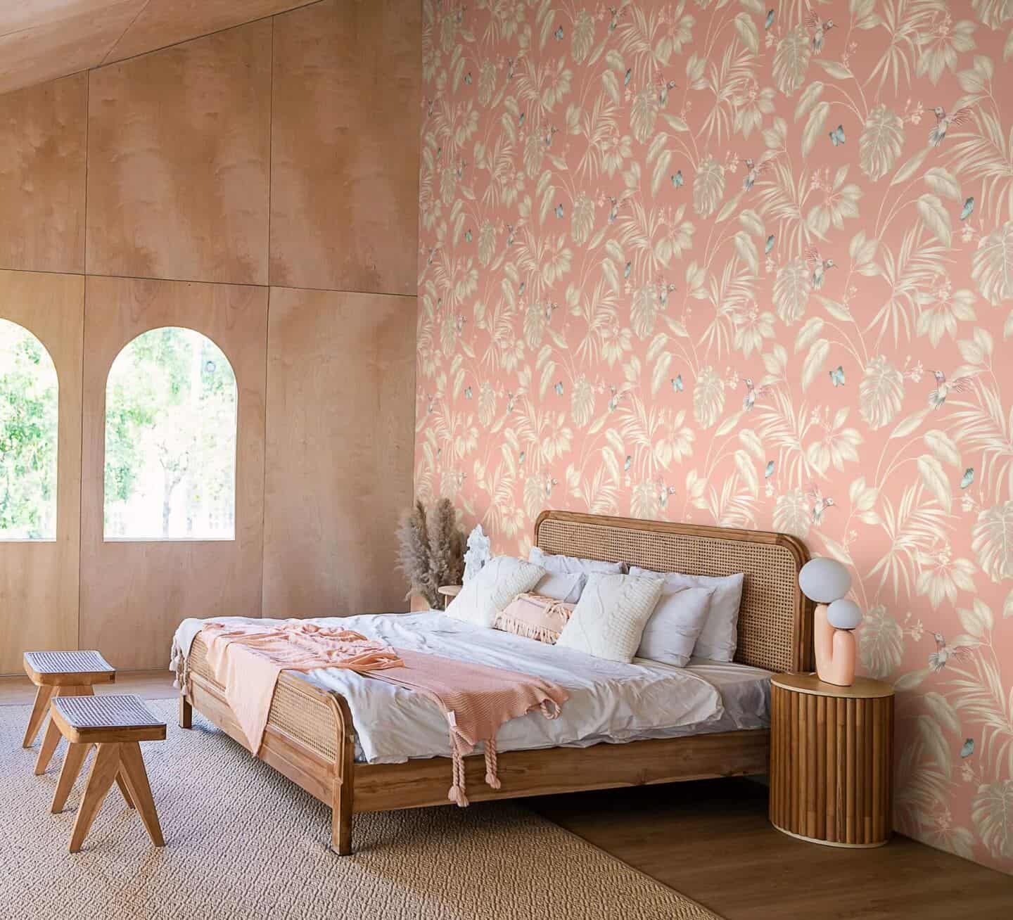 A bedroom featuring bed with rattan headboard and floral wallpaper in Pantone colour of the year 2024 Peach Fuzz