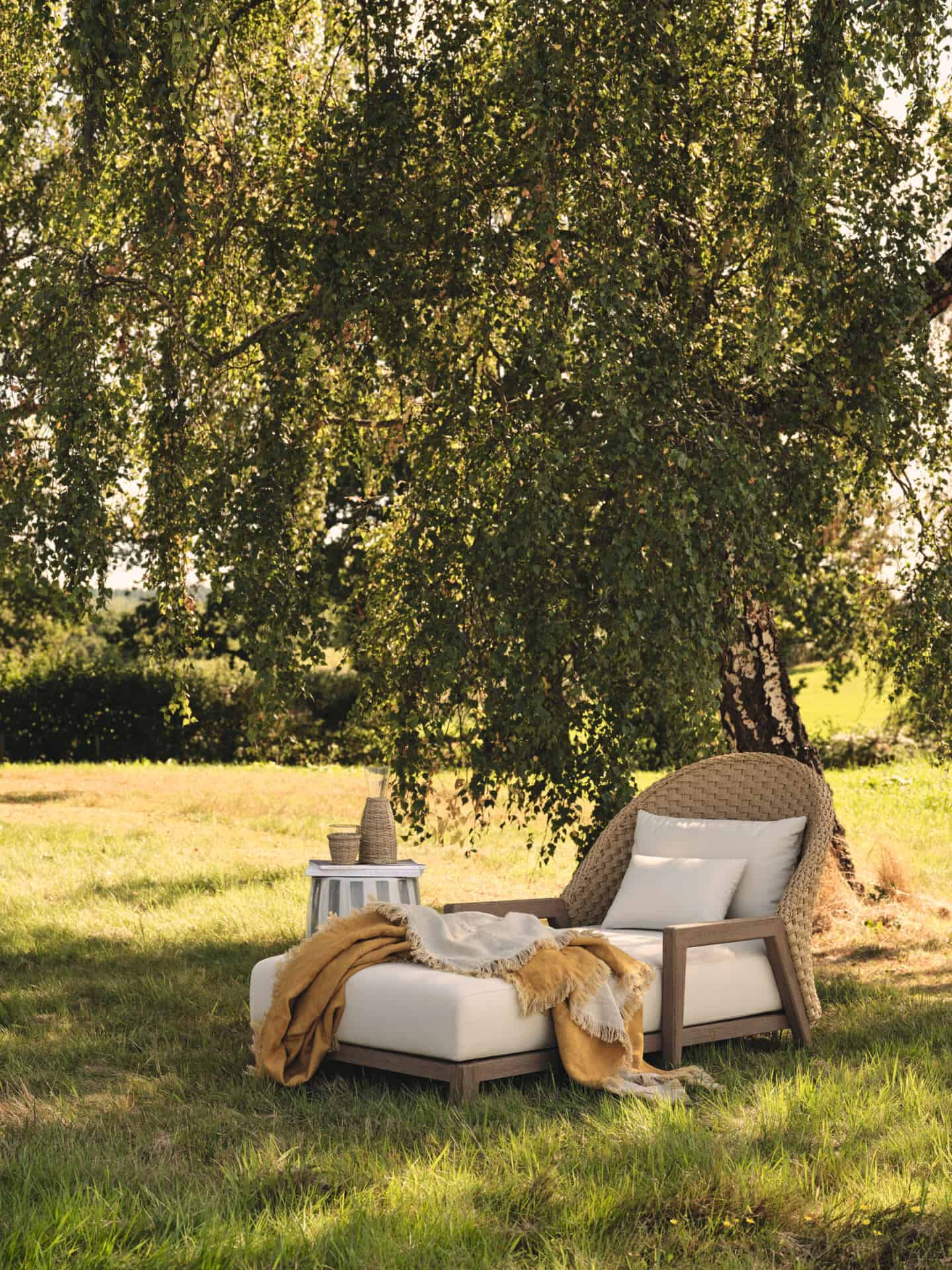 A lounger under a tree in a large garden