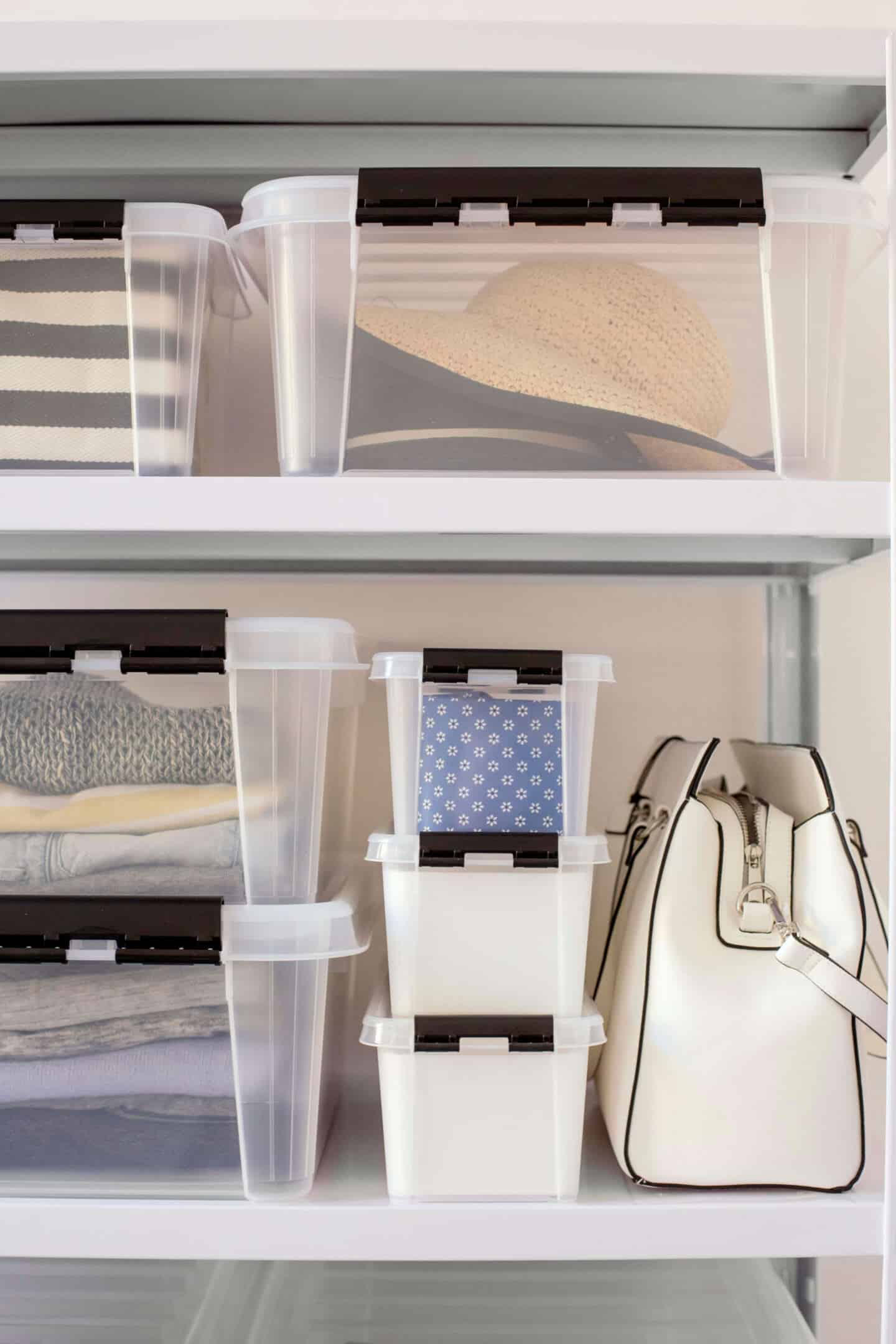 Clothes and accessories in clear storage boxes stacked on shelves next to a handbag