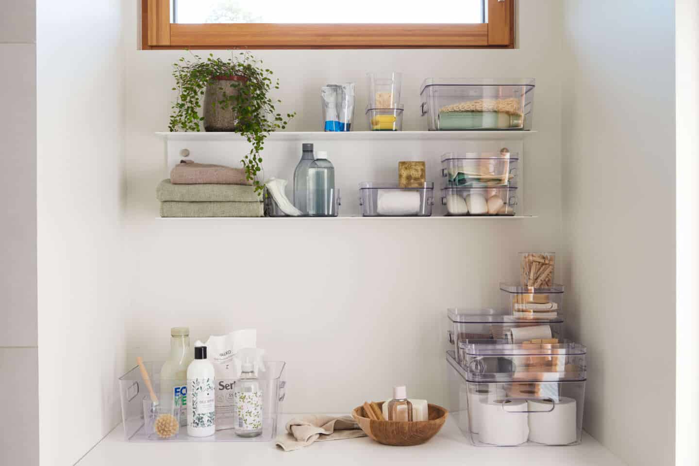 Make-up and bathroom accessories stored in clear boxes on shelves 