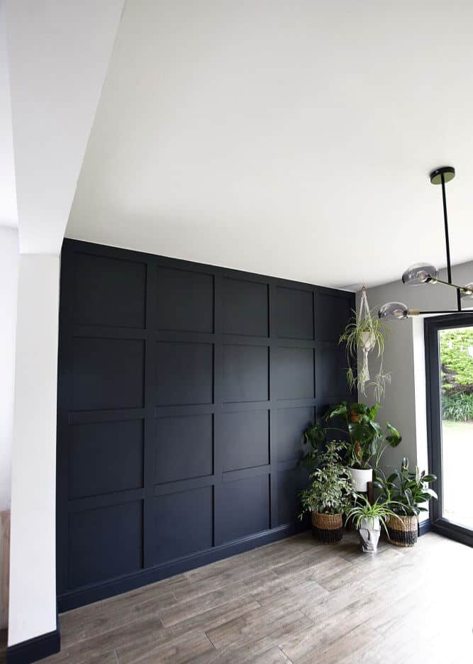 A blue wall in an empty dining room features wooden panelling in board and batten style