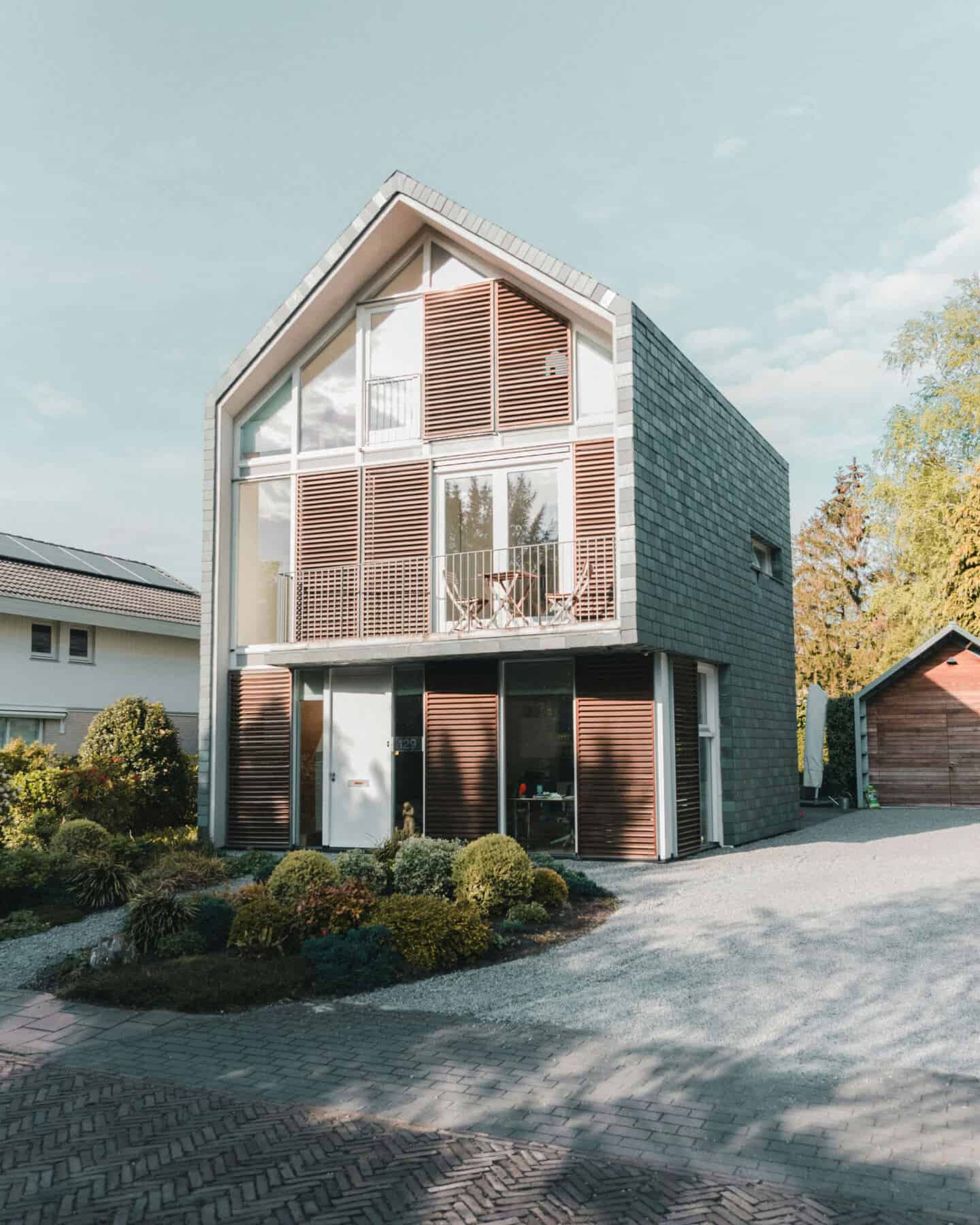 A 3-storey detached modern house with a gravel driveway