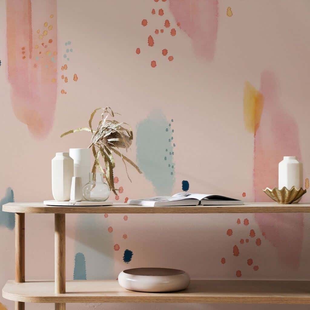 Pastel coloured abstract wallpaper behind a light wood console table