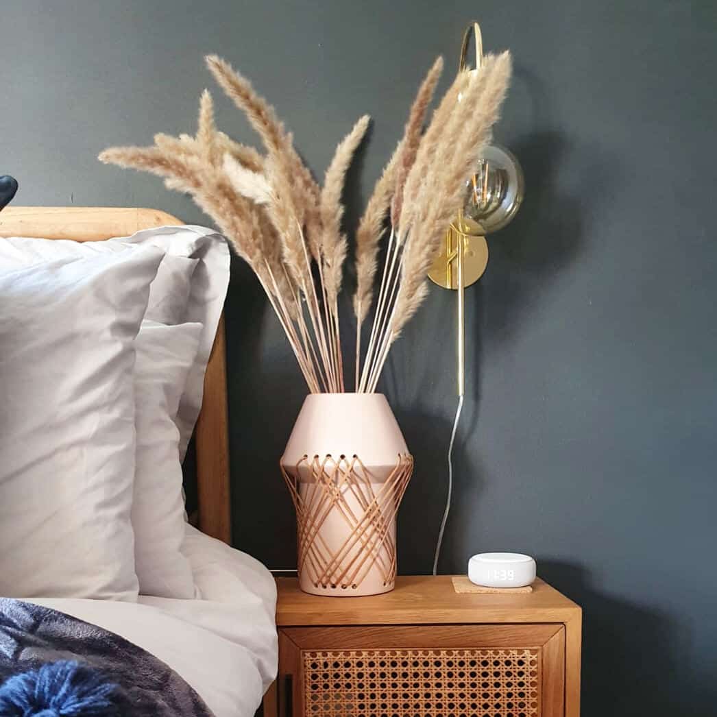 Affordable luxury homewares from Price & Coco Interiors. Vase of pampas grass on a rattan bedside table against a blue wall. 