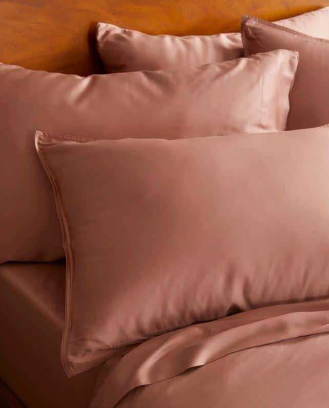 Close up of pink bamboo pillow cases on a wooden bed