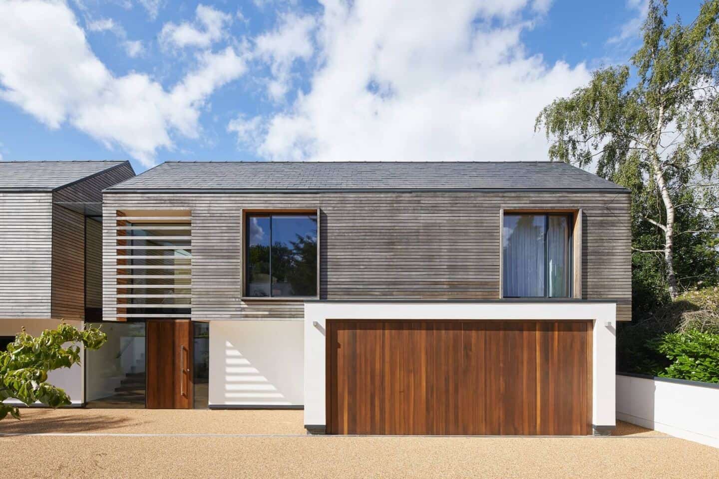 A contemporary wooden clad home with double garage with oak wooden garage doors