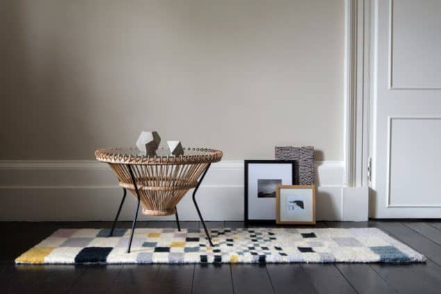 Coffee table placed on a geometric rug by Niki Jones