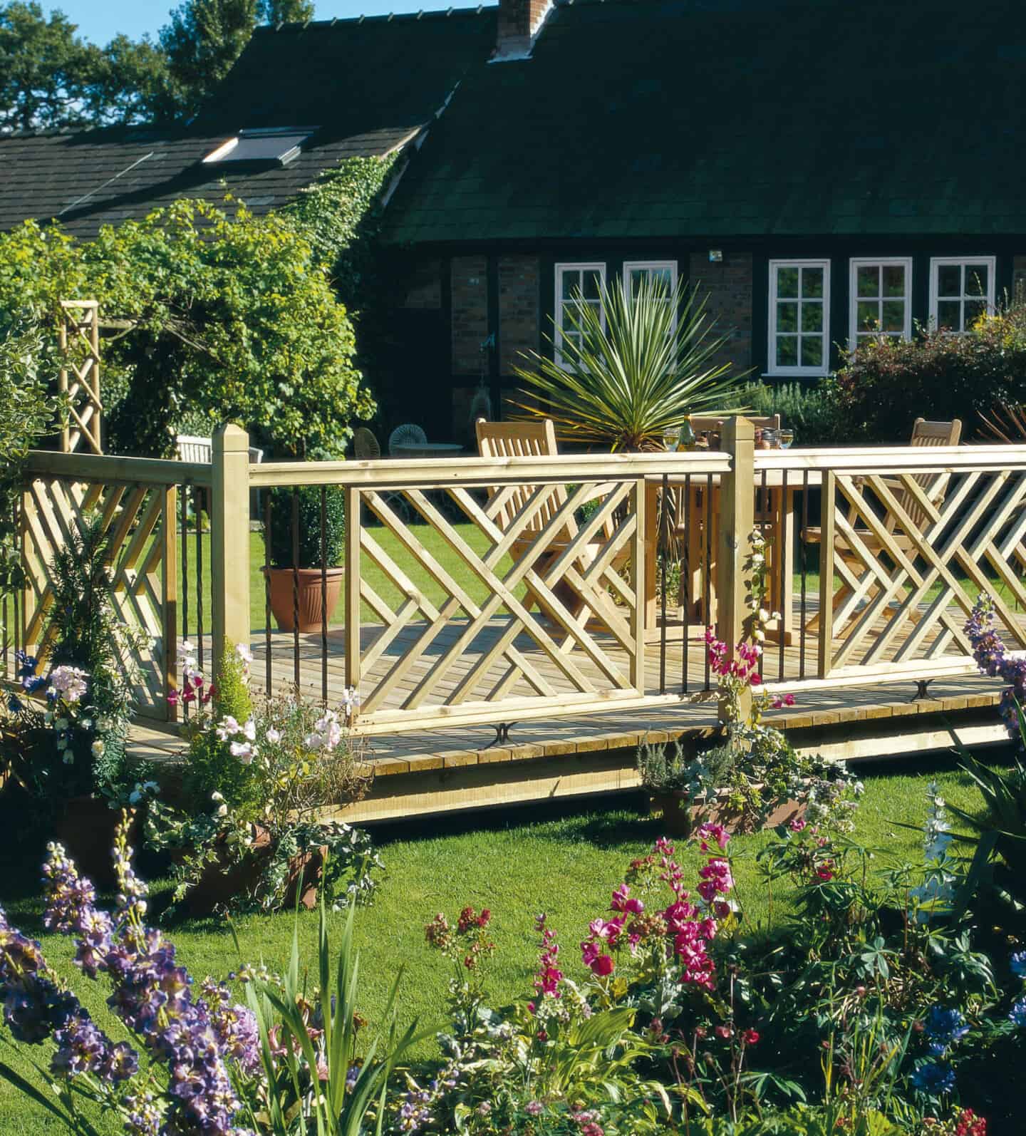 A wooden deck with trellis panels and a cottage in the background