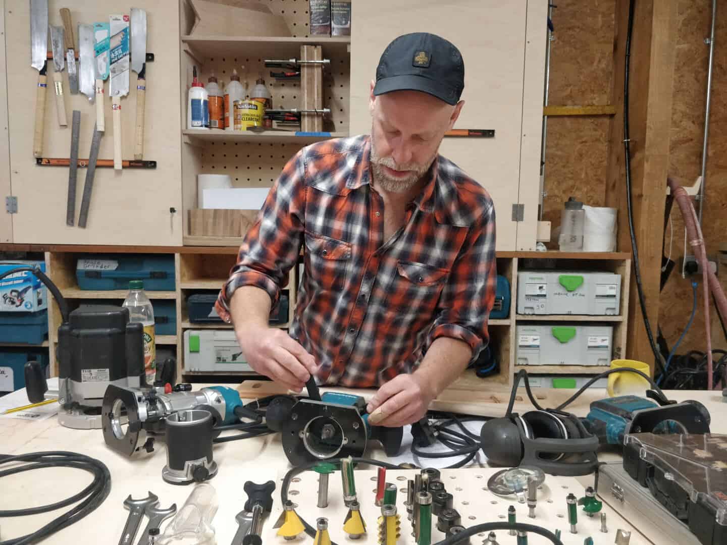 A white man demonstrates how to set up a router on a woodwork course at The Woodlab in Devon.