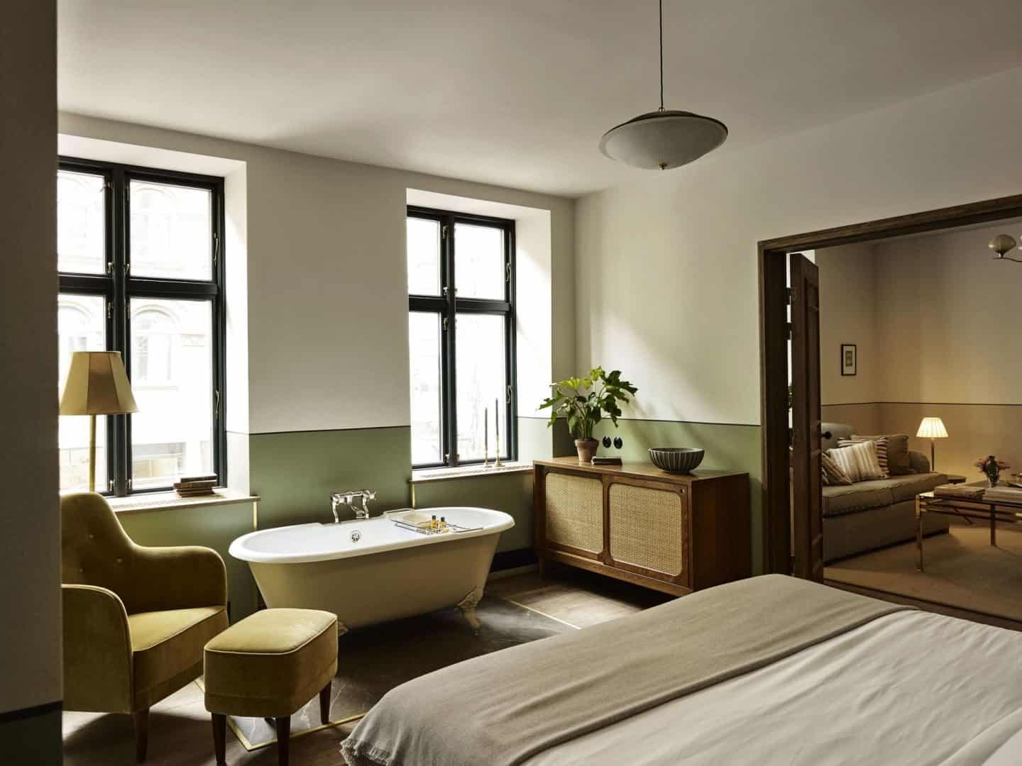 Sander Hotel, a design hotel in copenhagen. This bedroom has a colonial influence and feature muted earthy colours and natural material and a freestanding bathtub