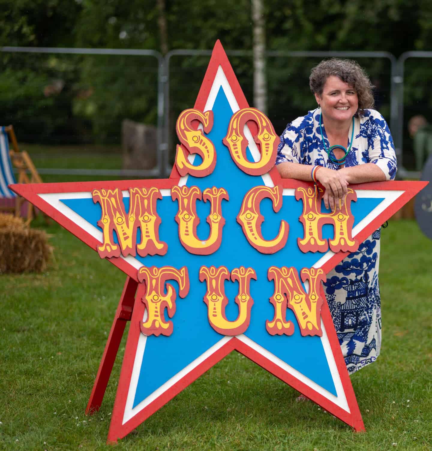 Sarah James, founder of The Craft Festival stood leaning on a star shaped sign that reads "so much fun" in a circus font 