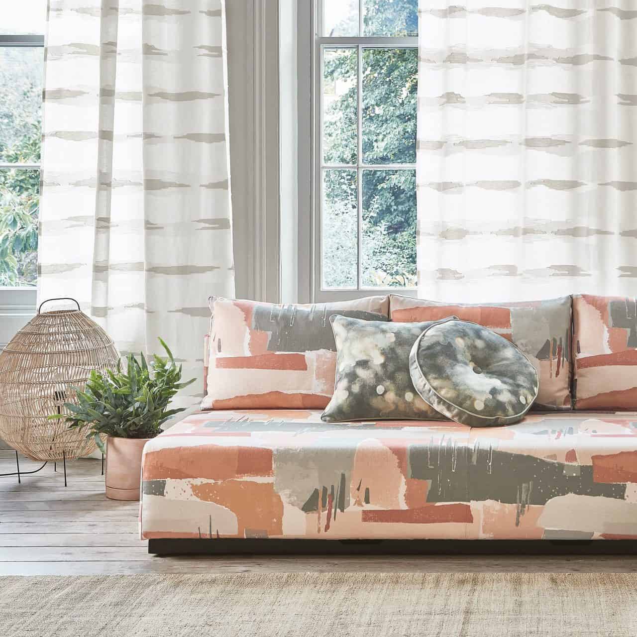 A living room featuring floor to ceiling sheet curtains on the windows