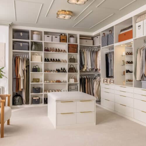 walk-in-wardrobe with walls lined with cupboards and a central island.