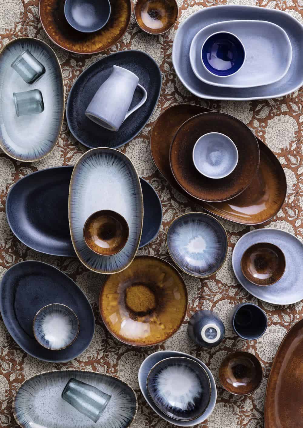 Shekåbba The Danish Home stocks a range of Danish homewares. A table seen from above full of ceramic serveware in earthy tones