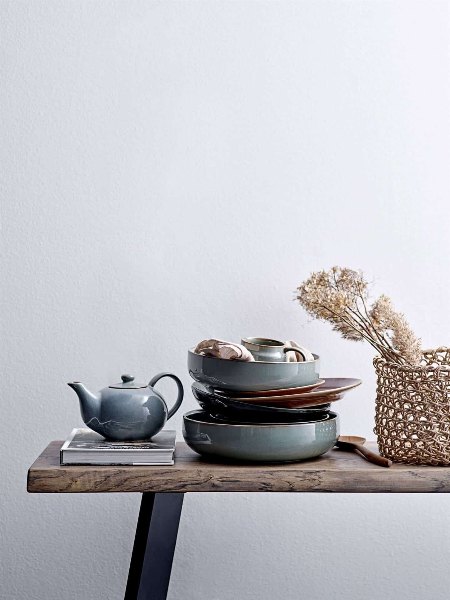 Shekåbba The Danish Home stocks a range of Danish homewares. A table stacked high with blue ceramic plates and a tea pot