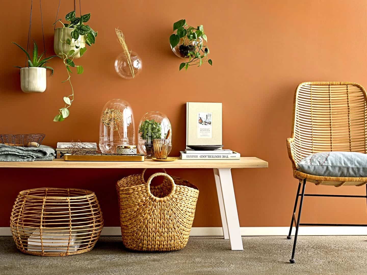 Shekåbba The Danish Home stocks a range of Danish homewares. A coffee table, baskets and rattan chair against a terracotta wall dotted with hanging plants