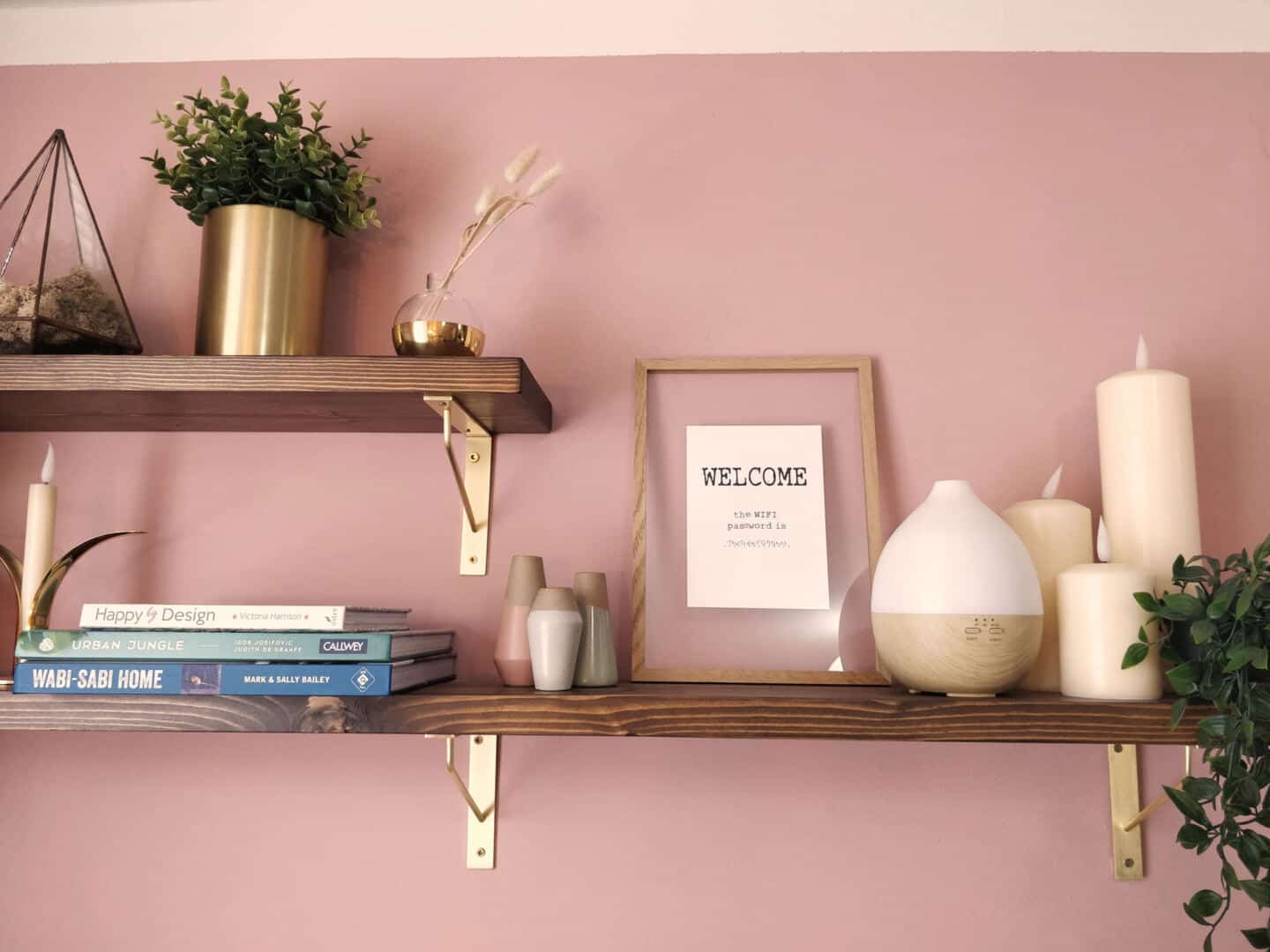 A shelf full of plants, candles, books and interior accessories