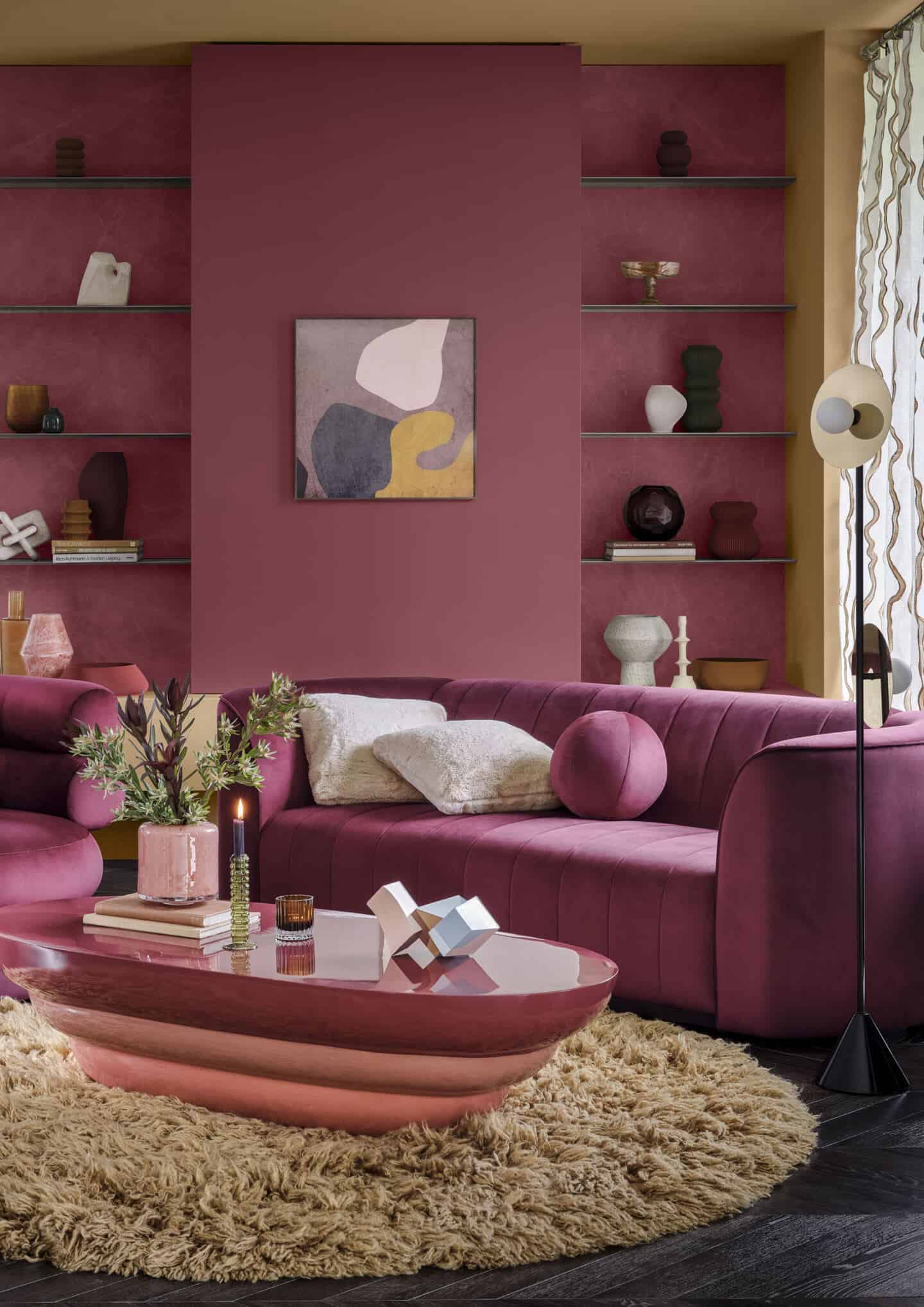 A pink living room featuring pink velvet sofa,, pink coffee table and built-in shelving on the wall