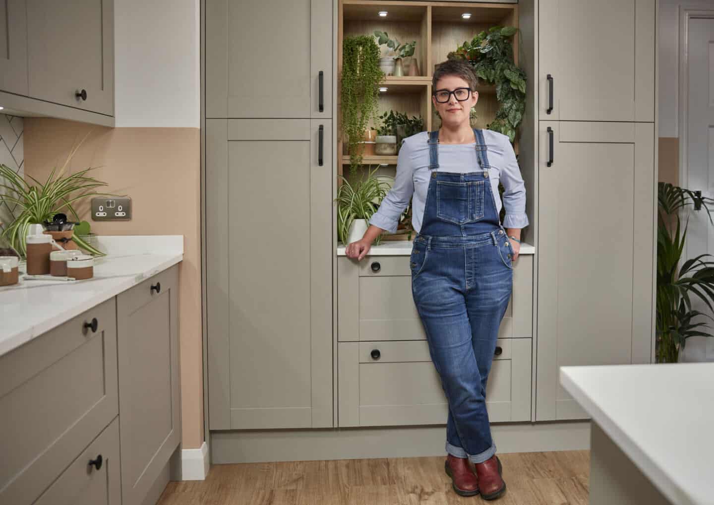 Blogger Stacey Sheppard stands in Magnet's Tatton Kitchen in front of built-in shelving full of plants. She shares tips for creating biophilic kitchen designs 