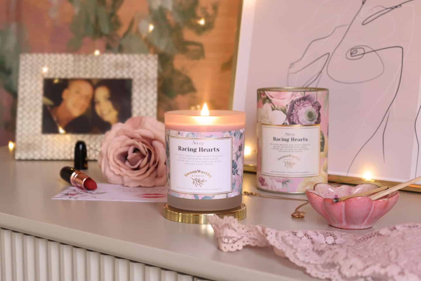 Racing Hearts, luxury eco-conscious scented candles by Swoon Worthy Scents on a chest of drawers in front of artwork and a photo of a couple.