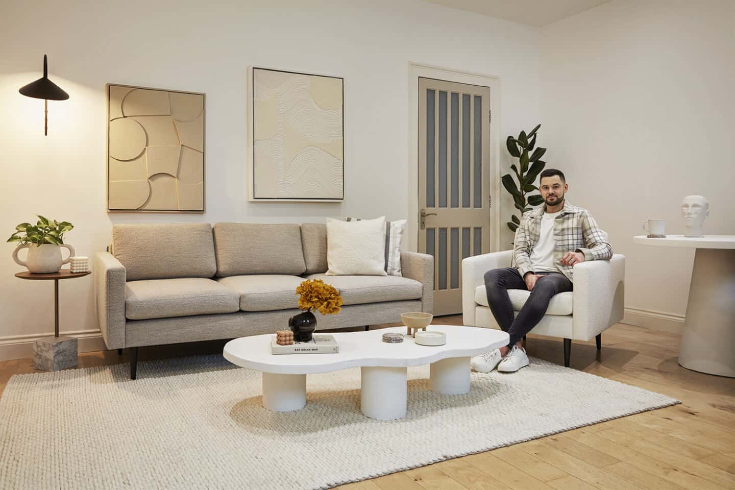 Interior designer Luke Arthur Wells sat on his new bouclé sofa collection designed in collaboration with Swyft Home