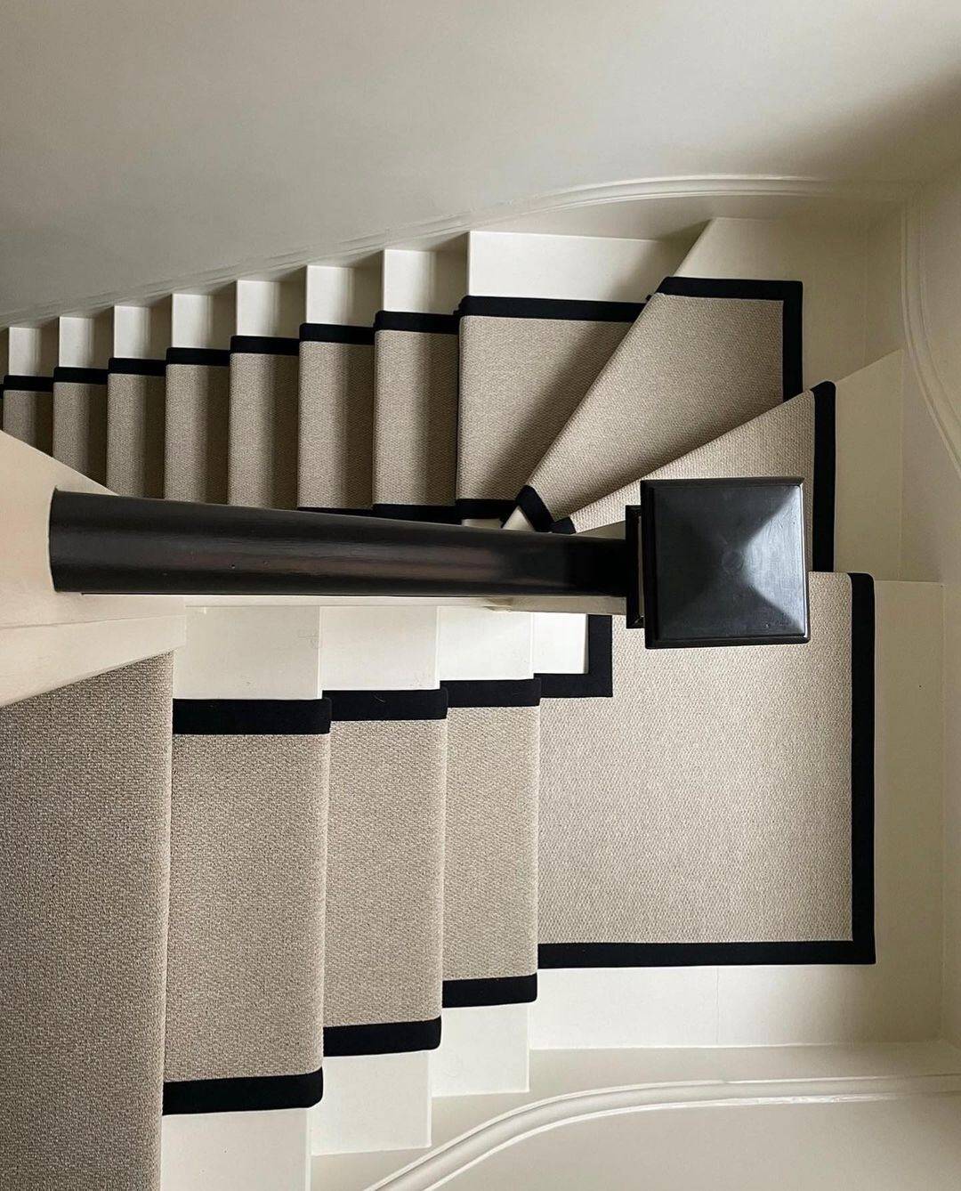 Grey carpet runner with black edging runs up a white staircase to create a dramatic statement