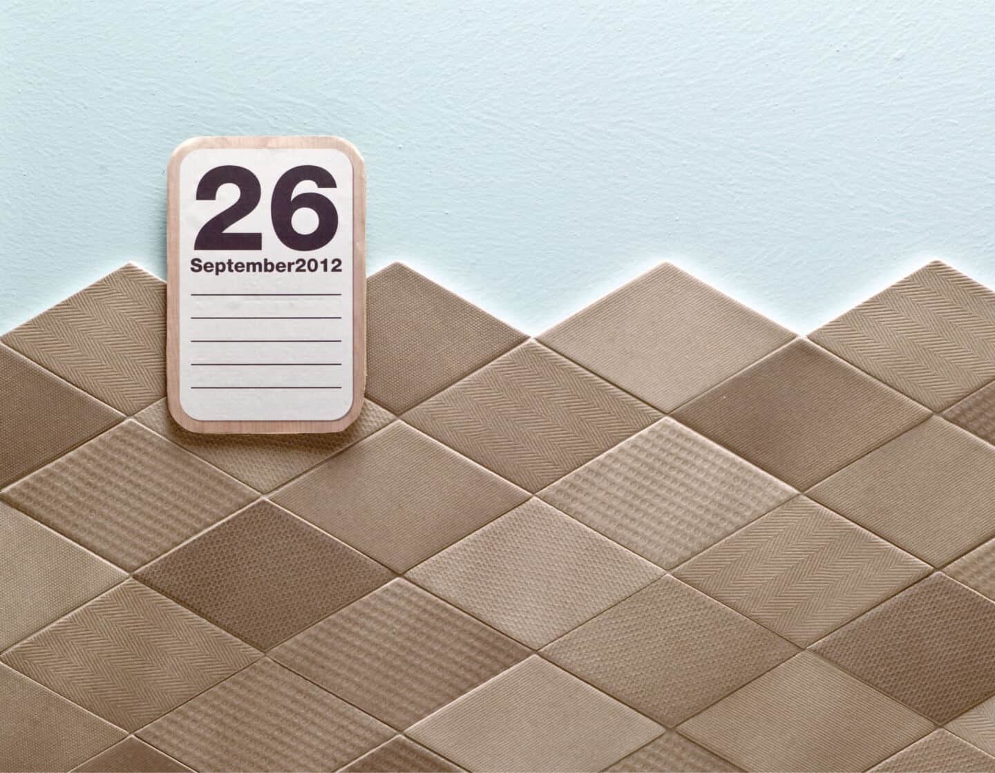 brown textured wall tiles.  A calendar hangs on the wall.