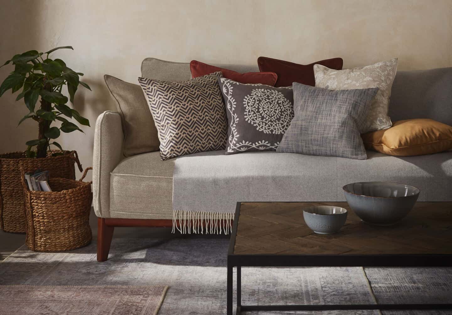 Textured Lives. Using texture in interiors to bring your home to life.  A sofa is behind a coffee table whoch is on a rug. The sofa is covered in textured cushions in an earthy colour palette