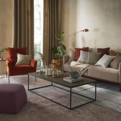 a living room featuring sofa, armchair and coffee table with lots of textured accessories