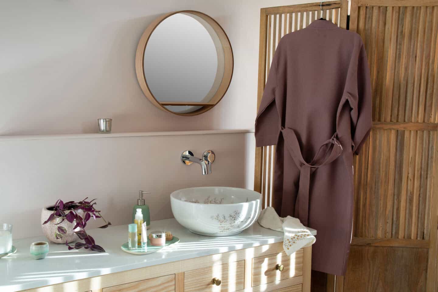 A round white bathroom sink with vanity. The sink is covered in delicate blossom pattern and rests on a countertop in a Japanandi style bathroom 